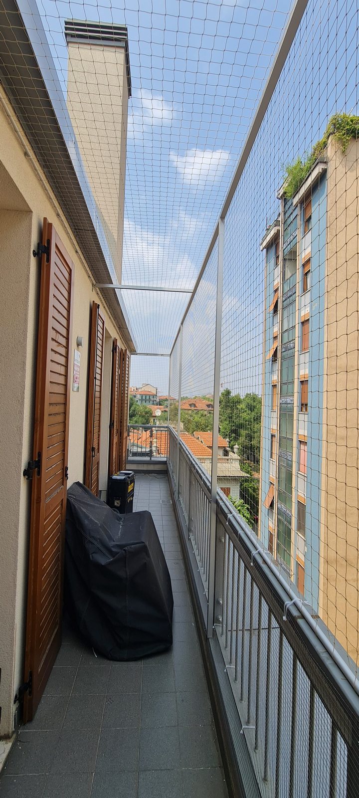 Balcone protetto con rete in nylon, fioriere e gatto che osserva il panorama